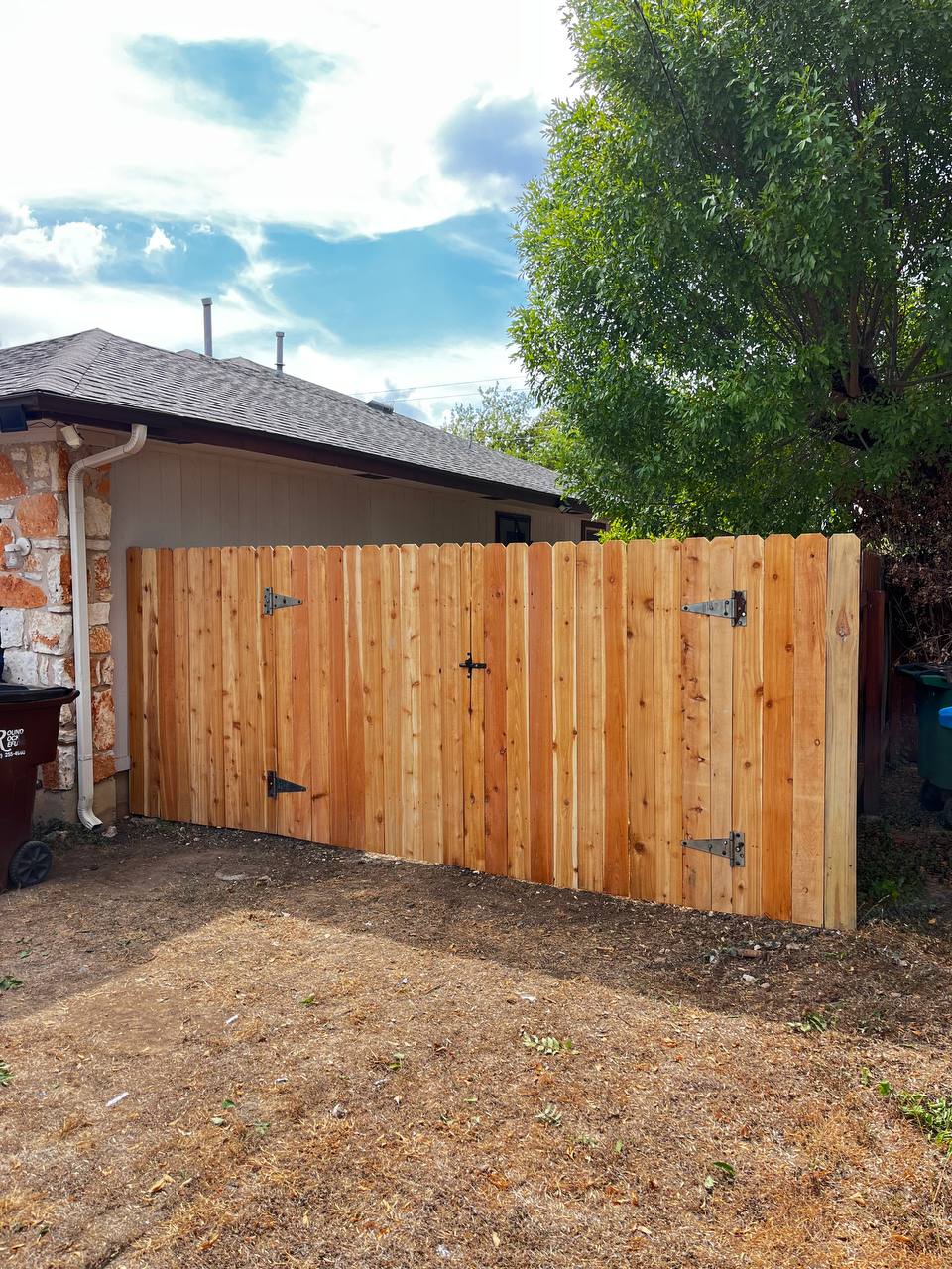 Double cedar gate and fence panel by stone house Cedar Park TX